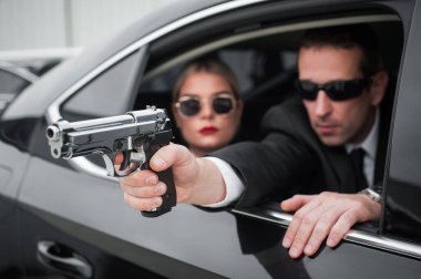 Silahlı, siyah takım elbiseli bir ajan arabada ünlüleri koruyor. Bodyguard ve VIP kişi güvenliği. Profesyonel polis koruması.