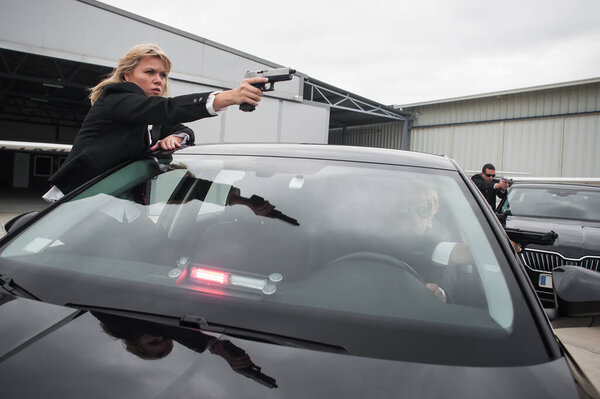 Professional armed team of female and male bodyguards protect celebrity person in car limousine. Bodyguard and VIP person security protection. Professional police agent in civilian black suit