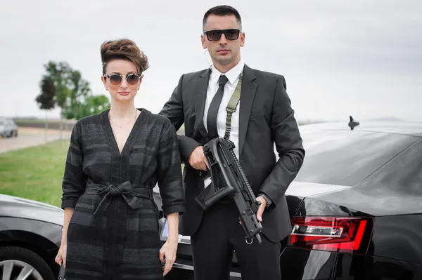Agent in civilian black suit with machinegun protect celebrity person. Bodyguard and VIP person security protection. Professional police agent