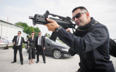 Egy civil fekete öltönyös ügynök géppuskával védi a hírességeket. Testőr és VIP személy biztonsági védelem. Hivatásos rendőrtiszt