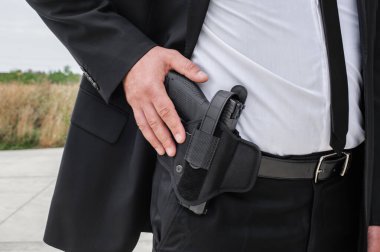 Özel ajan erkek korumanın eli bandocu kemeriyle yakın plan görüntüsü. Sivil takım elbiseli güvenlik polisi.
