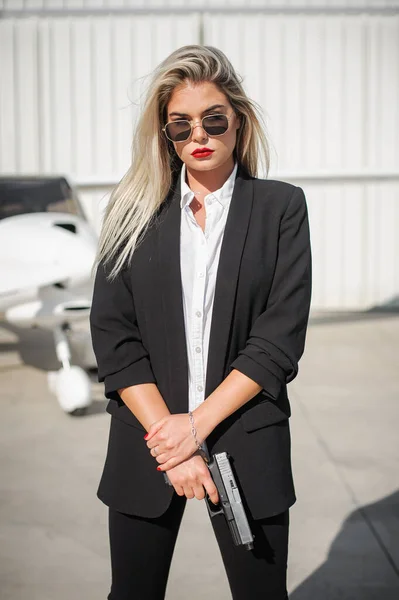 Beautiful professional female spy agent bodyguard posing with gun. Security police woman in civilian black suit. Close security protection