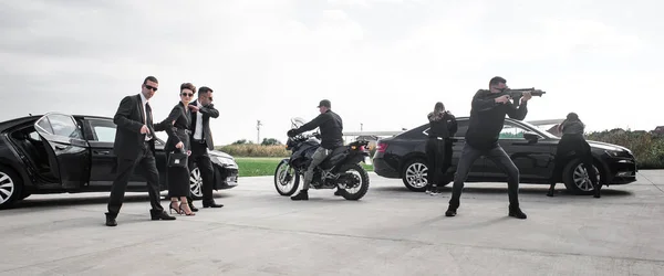 Tactical exercise training. An armed bodyguard security team protects a celebrity vip person in danger combat situation when attacked. Security police team in civilian black suit with sunglasses