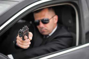 Polis taktik araba vurma eğitimi. Erkek casus ajan koruma limuzinden ateş ediyor. Sivil siyah takım elbiseli güvenlik polisi iş başında