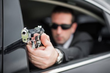 Polis taktik araba vurma eğitimi. Erkek casus ajan koruma limuzinden ateş ediyor. Sivil siyah takım elbiseli güvenlik polisi iş başında