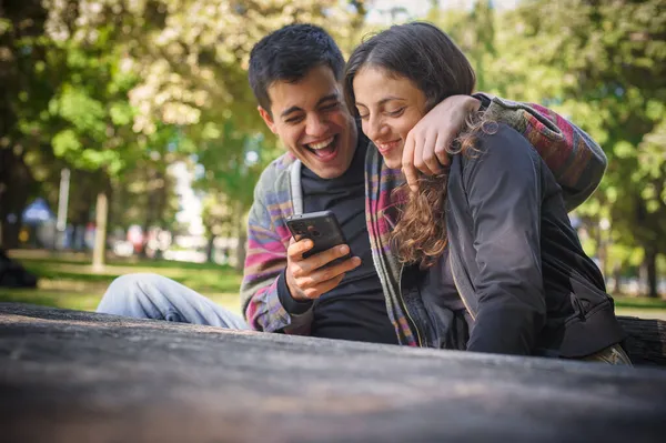 사랑하는 미소짓는 친구와 친구가 사진을 전화로 공원에서 즐기며 야외에서 — 스톡 사진
