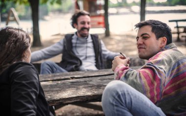 Bir grup rahat ve gülümseyen mutlu genç arkadaş, kadın ve erkek, kenevir marihuana esrar içiyorlar ya da açık hava parkında esrar içiyorlar. Gençler ot içiyor. Gerçek hayat sahnesi konsepti