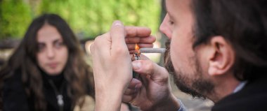 Marihuana ya da esrar sigarası yakan bir adam. Detaylı yakın görünüm. Gençler kenevir otları içerler. Gerçek hayat sahnesi konsepti