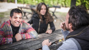 Bir grup rahat ve gülümseyen mutlu genç arkadaş, kadın ve erkek, kenevir marihuana esrar içiyorlar ya da açık hava parkında esrar içiyorlar. Gençler ot içiyor. Gerçek hayat sahnesi konsepti
