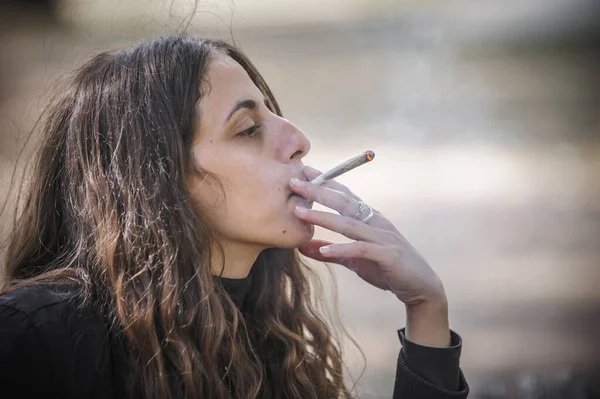 年轻女子吸食大麻大麻大麻甘贾或大麻混合香烟的特写 随便抽绿草的女青年 真实生活场景的概念 — 图库照片