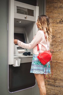 Genç, sıradan, seksi bir kadın, raptiye yazıyor ve ATM 'den para alıyor. Finans, kredi kartı, para çekme. ATM 'den bir kart aldı.