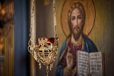 Kilisede dini ikonografi ve ikonostaz önünde asılı duran pirinç ve camdan yapılmış Hristiyan yağlı mumlarının detaylı görüntüsünü kapatın.