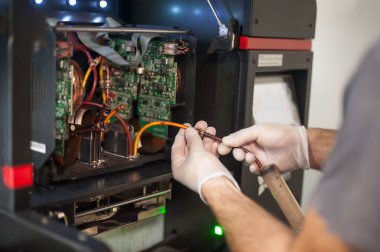 Elektrik mühendisi operatörünün yakın plan detaylı görüntüsü dijital matbaa ofisindeki büyük kaliteli endüstriyel yazıcı ve çizer makinesini tamir ediyor