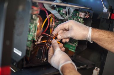 Elektrik mühendisi operatörünün yakın plan detaylı görüntüsü dijital matbaa ofisindeki büyük kaliteli endüstriyel yazıcı ve çizer makinesini tamir ediyor