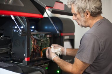 Elektrik mühendisi operatörünün yakın plan detaylı görüntüsü dijital matbaa ofisindeki büyük kaliteli endüstriyel yazıcı ve çizer makinesini tamir ediyor