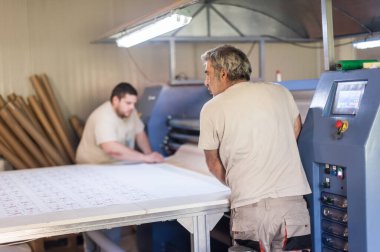 İki teknisyen işçi, dijital matbaa ofisinde büyük kaliteli endüstriyel tekstil süblimleşme Roller ısı baskı makinesi üzerinde çalışıyor.