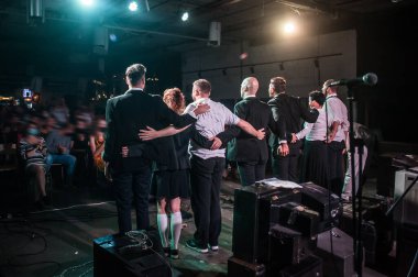 Loud applause for actors. Large group of artists bow to audience on stage in theatre. Obeisance to the spectators who applaud and give great support to the actors. Back view clipart