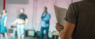 Sahnenin arkasında. Oyunun yönetmeni senaryoya göre oyunu oyuncularla prova ediyor.