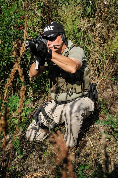 Ormanda makineli tüfekle ateş eden bir asker. Doğal açık hava askeri savaş eğitimi.