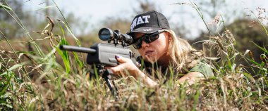 Dişi asker askeri hedef alıyor ve bir askeri eğitim alanına keskin nişancı tüfeğiyle nişan alıyor. Özel kuvvetlerdeki kadın. Ateşli silahlar ve taktik eğitimi. Atış poligonu