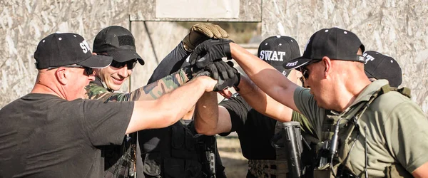 Özel anti-terörist birim askerleri bir eğitim görevini başarıyla tamamladıktan sonra el ele bir grup selamı veriyorlar. Ateşli silahlar ve taktik eğitimi.