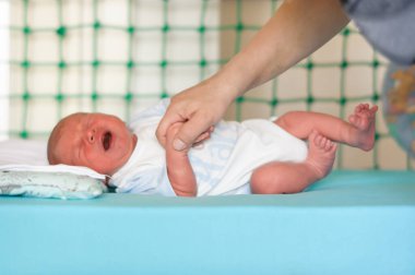 Sevimli, küçük, tatlı, yeni doğmuş bir bebek, şefkatli annesi elini tutarak onu sakinleştirmeye ve teselli etmeye çalışırken güçlü bir şekilde ağlar. Mide krampları