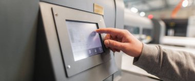 Dijital matbaa ofisindeki dokunmatik ekran monitör istasyonunun giriş ve çıkış durumunu kontrol eden teknisyen operatörü