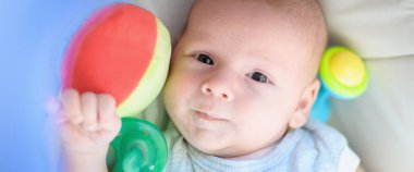 Bir sürü renkli plastik oyuncağı ve kafasının etrafında çıngırağı olan bir bebek. Ayrıntılı yakın plan portre. Aşk ve aile duyguları