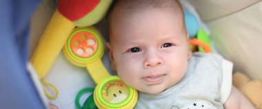 Komik çocuk konuşuyor ve oyuncak telefon kulaklığını faytonda kullanıyor. Kafasında bir sürü renkli plastik oyuncak ve çıngırak var. Ayrıntılı yakın plan portre. Aşk ve aile duyguları