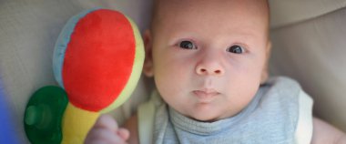 Bir sürü renkli plastik oyuncağı ve kafasının etrafında çıngırağı olan bir bebek. Ayrıntılı yakın plan portre. Aşk ve aile duyguları