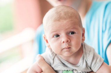 Close-up detail portrait of cute little peaceful newborn baby boy child face with beautiful open eyes. Love and family emotion