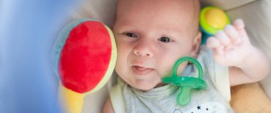 Bir sürü renkli plastik oyuncağı ve kafasının etrafında çıngırağı olan bir bebek. Ayrıntılı yakın plan portre. Aşk ve aile duyguları