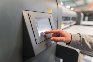 Dijital matbaa ofisindeki dokunmatik ekran monitör istasyonunun giriş ve çıkış durumunu kontrol eden teknisyen operatörü