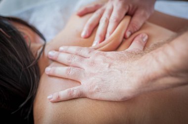 Female receives a back massage in a medical setting from a male masseuse, in spa salon - indoors