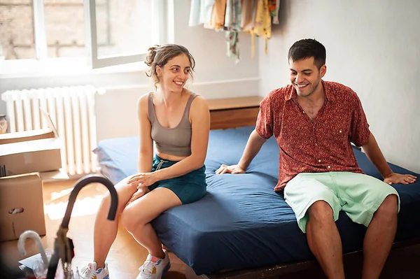 Cheerful young couple making bed, having fun at home. Doing house chores together, cleaning up in bedroom after sleeping. Concept of making the bed as a couple.