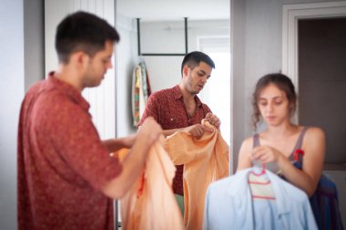 Giyinmeye çalışan, yatak odasındaki dolabın arkasında durup eğlenen genç ve çekici bir çift.
