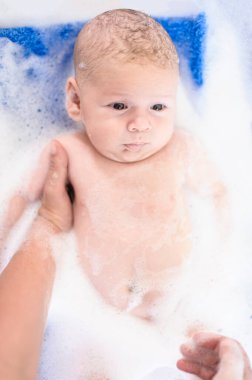Bebek banyosu zamanı. Su ve köpüklü küvette banyo yapan anne hakkında detaylı bir görüş.