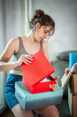 Genç bir çift yeni evlerine taşınıyor. Kutular, paketler ve diğer şeylerle çevrilidir..