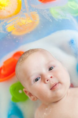 Bebek banyosu zamanı. Su ve köpüklü küvette banyo yapan anne hakkında detaylı bir görüş.