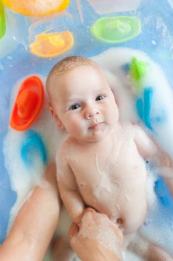 Bebek banyosu zamanı. Su ve köpüklü küvette banyo yapan anne hakkında detaylı bir görüş.
