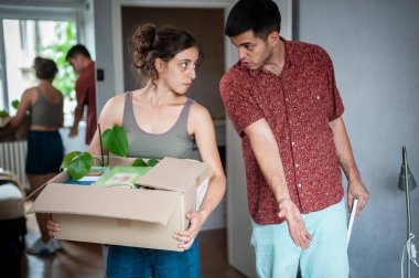 Genç bir çift yeni evlerine taşınıyor. Kutular, paketler, renkli gardırop ve diğer şeylerle çevrili..