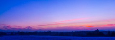 Kış günbatımı gökyüzü. Polonya 'da bir ormanda gün batımı