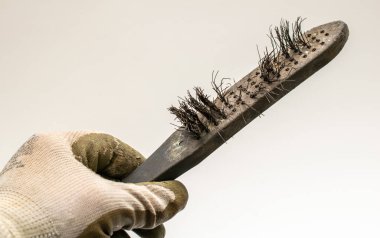 Eski bir tel fırça, elinde tutuyordu.