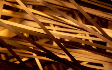 Sarı ışıkta kaotik bir şekilde sıralanmış metal şeritler.