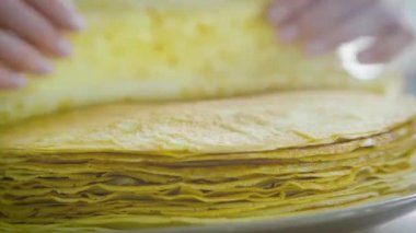 Evdeki mutfakta krep kızartıyorum. Bir kadın geleneksel Rus krepleri hazırlıyor. Kadın tabakta krep ütülüyor..