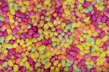 Close up macro photograph of bright multicolored sugar coated puffed maize and rice candy abstract background shot from above