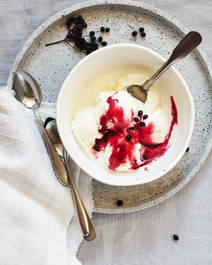 Keten bir masa örtüsünün üzerindeki kasede çilek soslu vanilyalı dondurma..