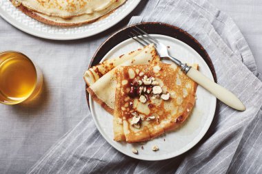 Fransız krepleri, ballı ve fındıklı keten masa örtüsünde..