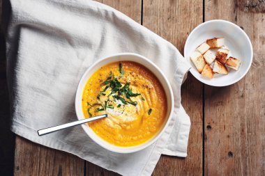 Tahta bir masada beyaz bir kasede havuçlu krema çorbası..