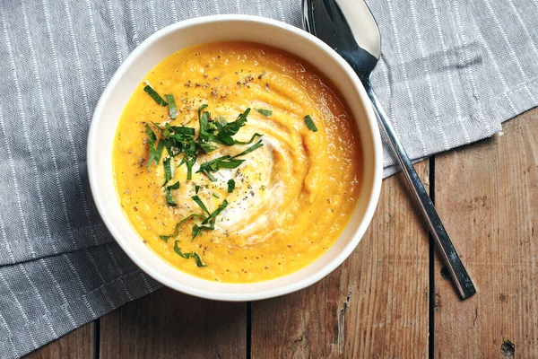 Tahta bir masada beyaz bir kasede havuçlu krema çorbası..